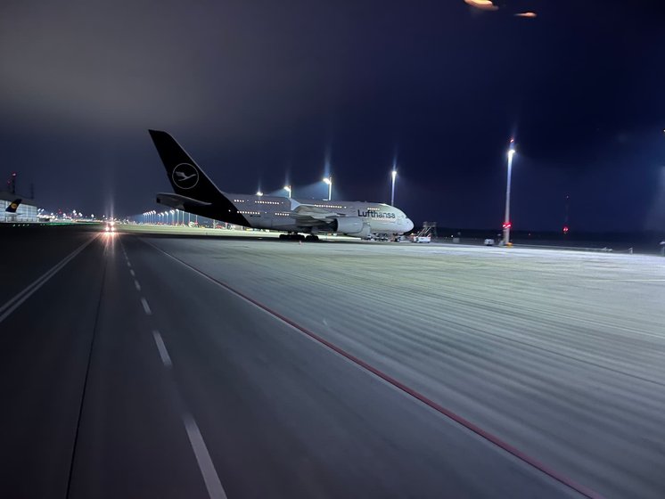 Lufthansa-Flugzeug auf dem Rollfeld des Münchner Flughafens bei Nacht.