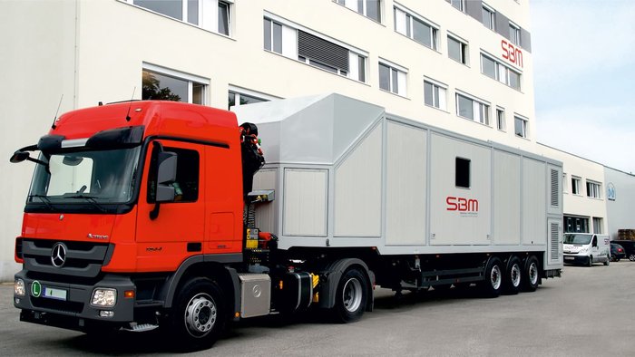 Fahrbarer Mischer auf LKW-Anhänger vor Gebäude nach abgeschlossenem Service