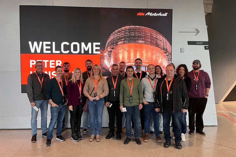 Willkommen bei KTM Motohall: Betriebsausflug 2024 Team Hasieber in der KTM Motohall vor einem Begrüßungsschild