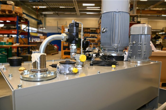 Hydraulikaggregat in der Fertigung Graues Hydraulikaggregat mit Elektromotor und Ventilen in der Werkstatt